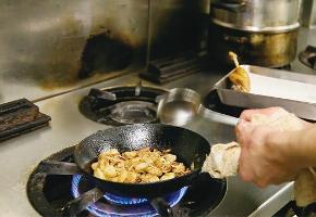 A Western cook frying ingredients in a frying pan