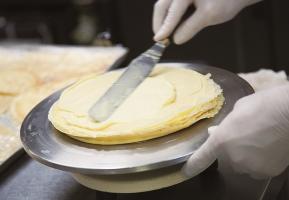 A Western confectioner wears cream on cake dough