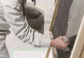 A plasterer wears a wall using a kote