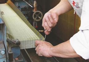 A tatami craftsman sews the edge of a tatami mat