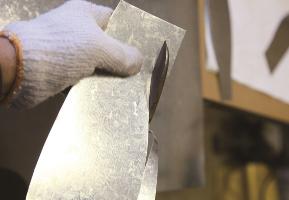 A sheet metal craftsman cutting a metal plate