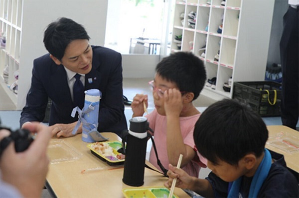 Mayor staring at children eating school lunch